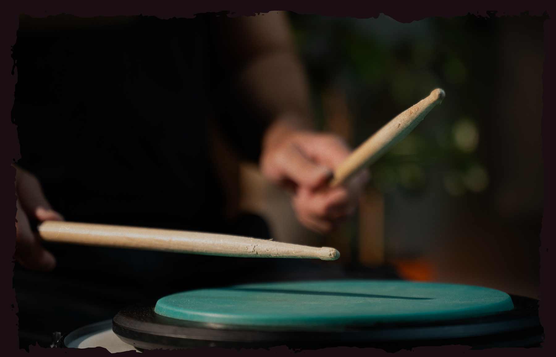 Female teen playing acoustic drums with headphones.